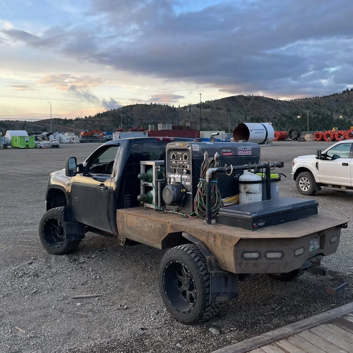 Black welding rig pickup with tanks, reels, tools, and equipment mounted on the rear flatbed.