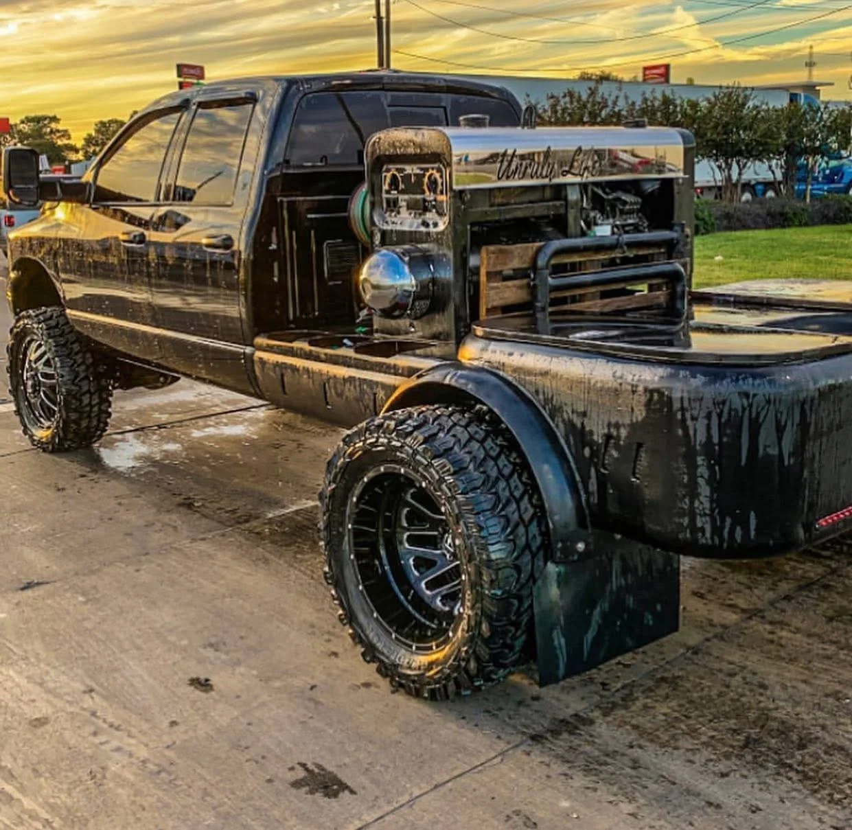Black pickup with a custom welding flatbed, mounted equipment, storage, hose reels, and large off-road tires.